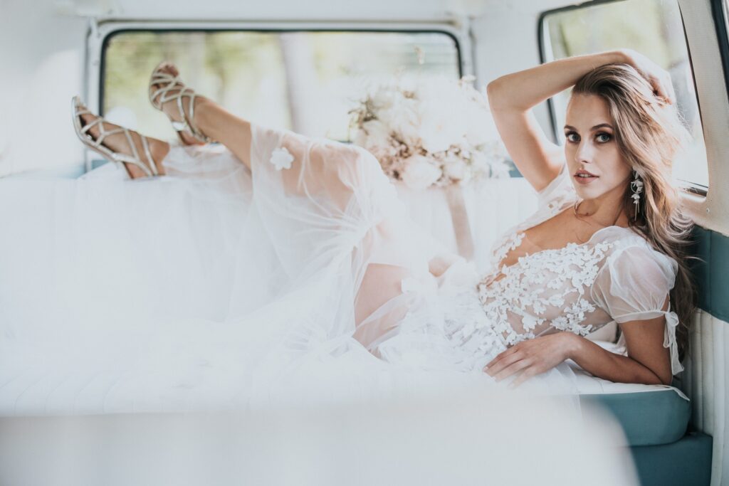 a woman in a white dress lying on a car