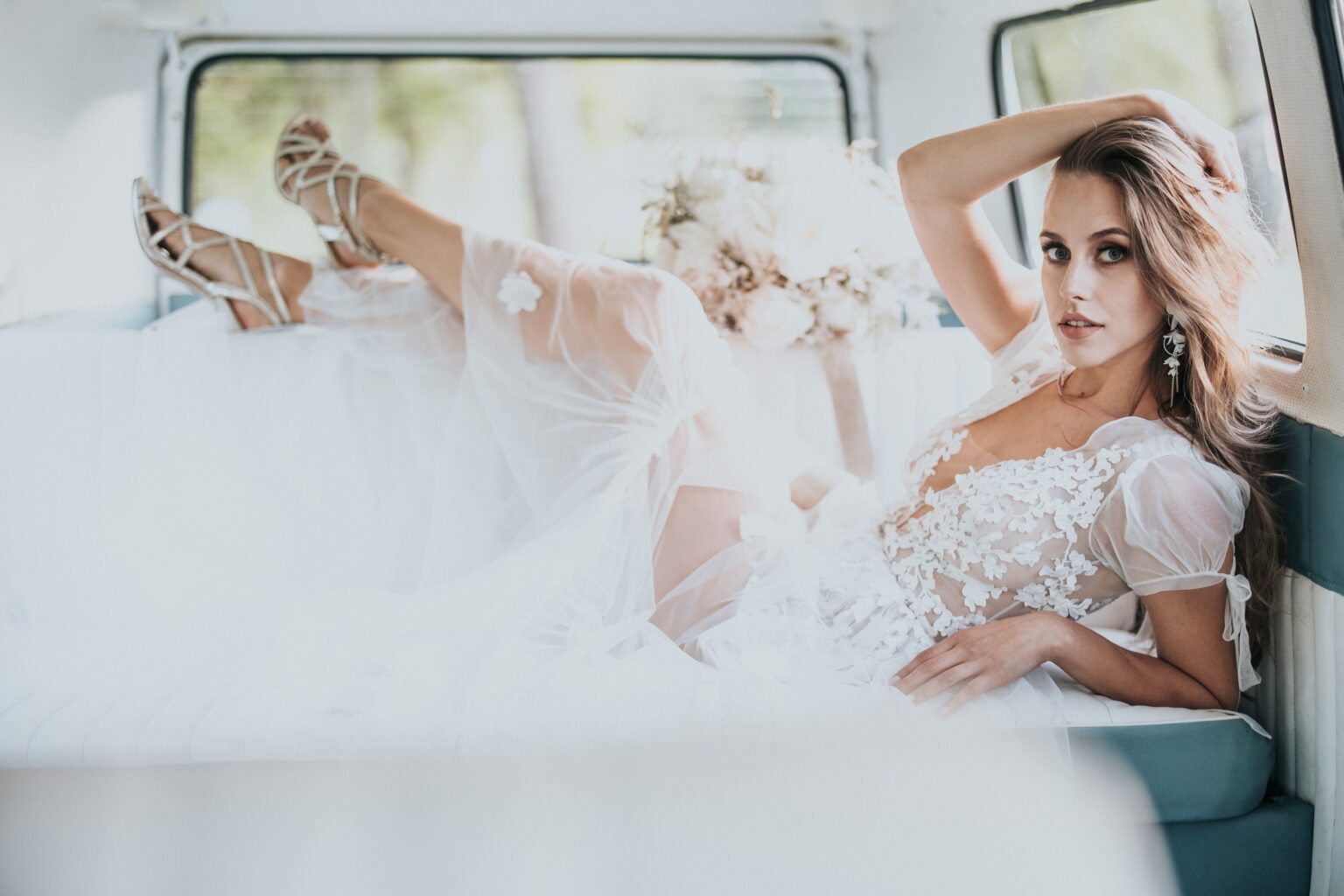 a woman in a white dress lying on a car
