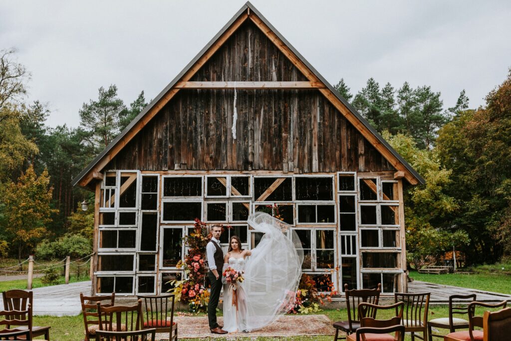a man and woman posing for a picture in front of a barn