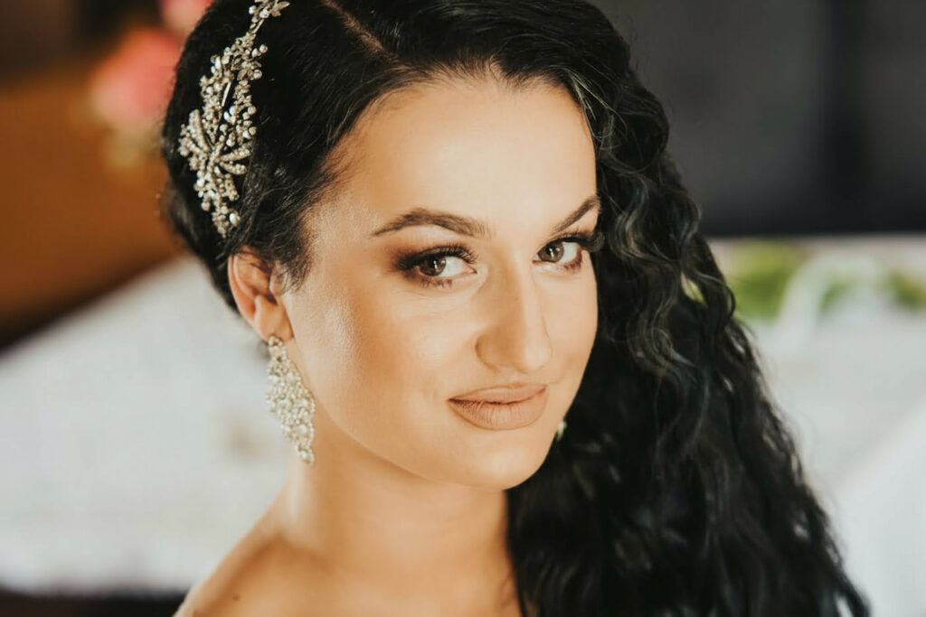 a woman with long black hair, diamond earrings and a golden tiara