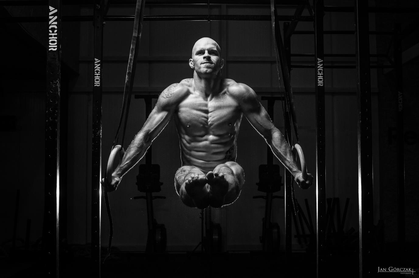 a man doing dips on gymnastic rings in black and white