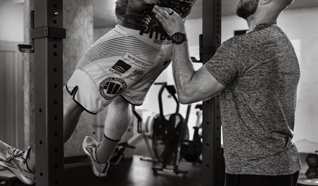 a man lifting helping another man do a pull up