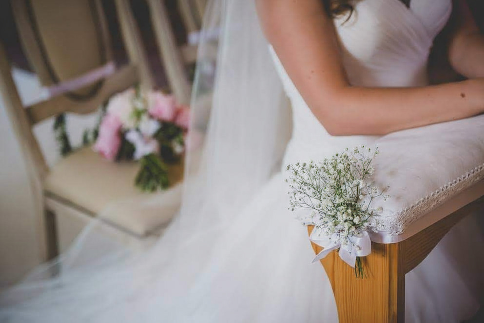 a bride in a white dress with flowers on the back of a chair